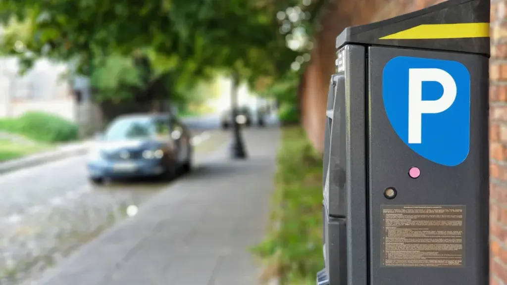 Moodne parkimisautomaat Pärnu tänaval, kus on näha autosid ja linnakeskkonda.