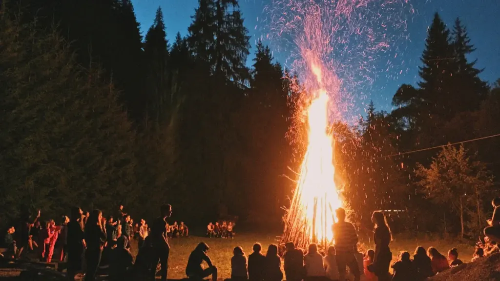 Suur jaanituli õhtuhämaruses, mille ümber istuvad inimesed naudivad jaanipäeva tähistamist.