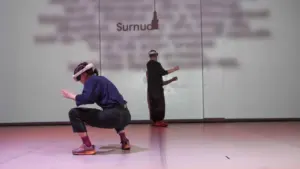 Kaks inimest virtuaalreaalsuse prillidega tegemas liigutusi heledal taustal, kus on kiri Surnud.