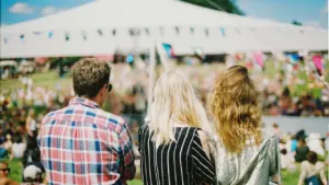 Kolm noort inimest vaatavad suvisel ajal vabaõhuüritust või festivali avatud väljakul